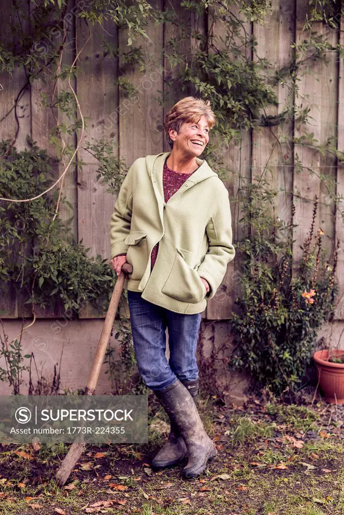 Portrait of mature woman leaning on spade in garden