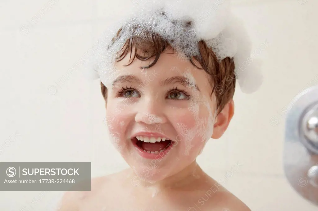 Boy in bath with bubbles on his head