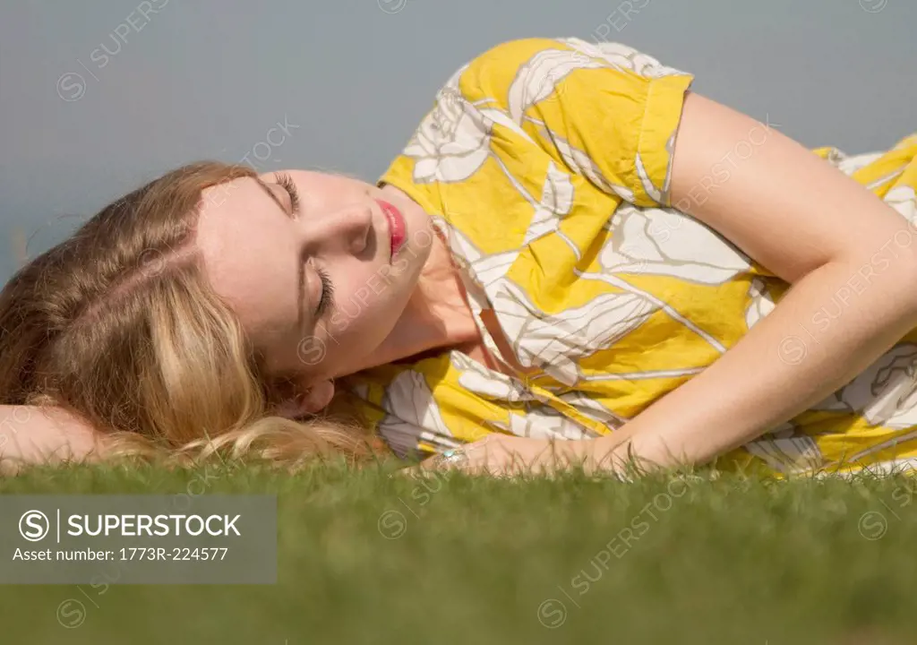 Portrait of young woman daydreaming on grass
