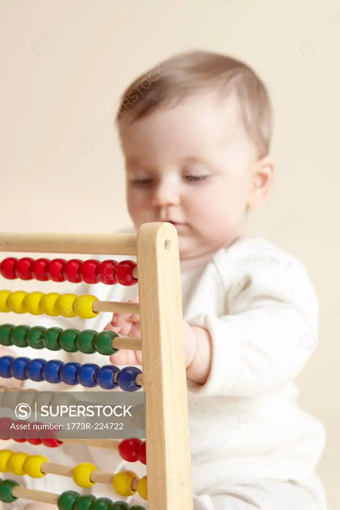 Close up studio portrait of baby girl playing with abacus