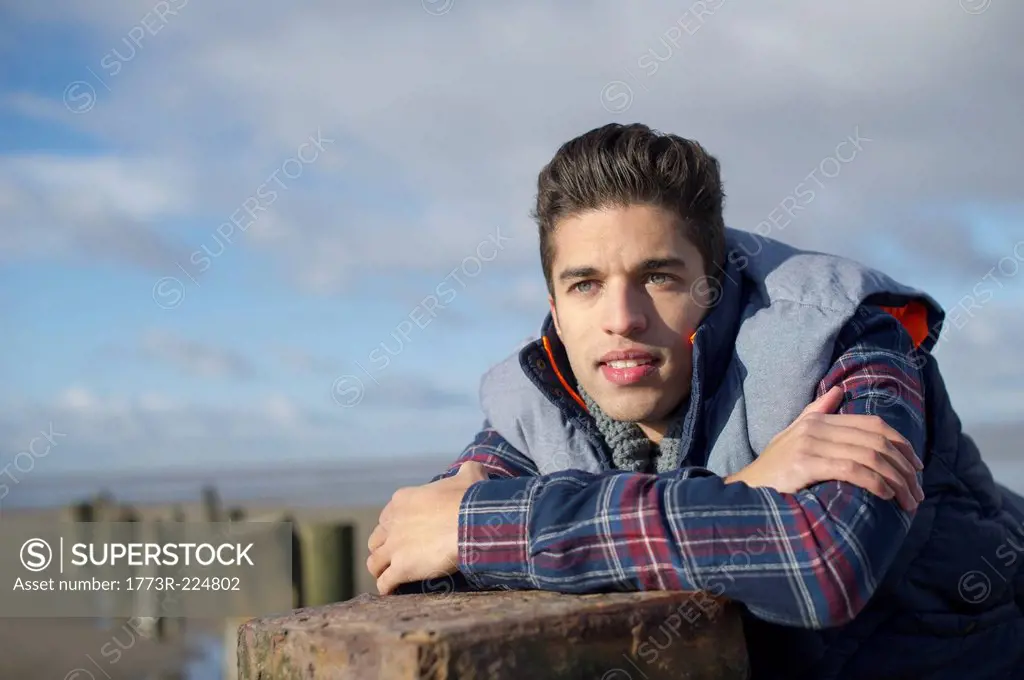 Young man leaning on groyne, Brean Sands, Somerset, England