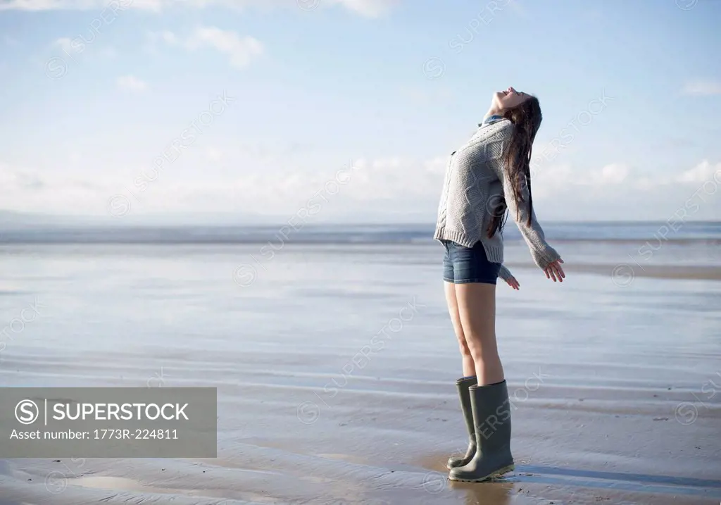 Young woman standing on beach looking up, Brean Sands, Somerset, England