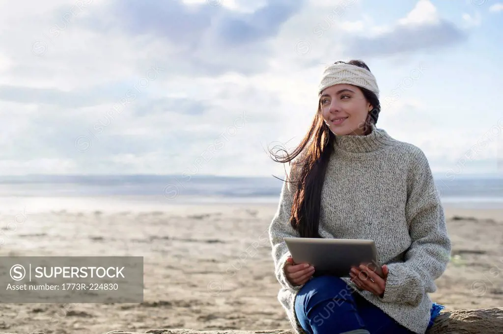 Young woman using digital tablet, Brean Sands, Somerset, England
