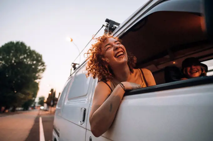 Happy young woman leaning out of van window