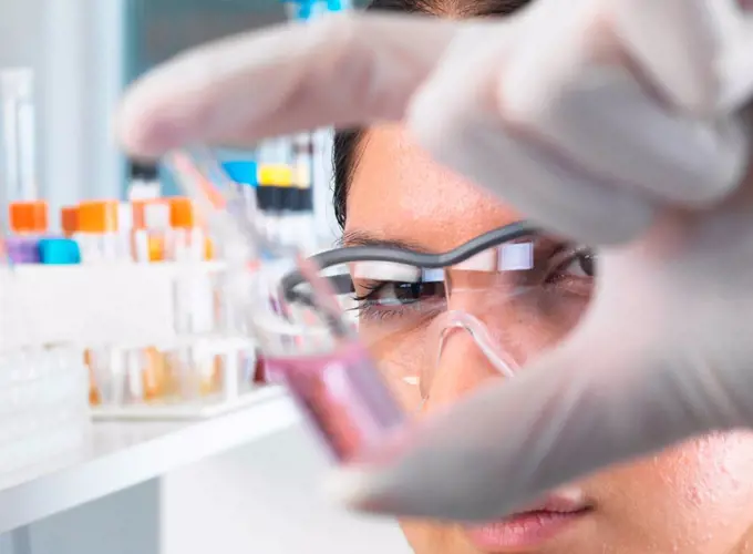 Close up of female scientist trialing medical drug ampule in laboratory