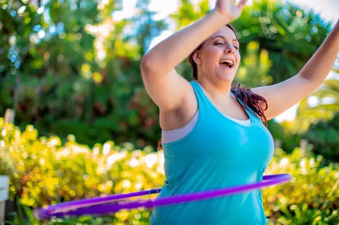 Woman exercising with hula hoop in garden