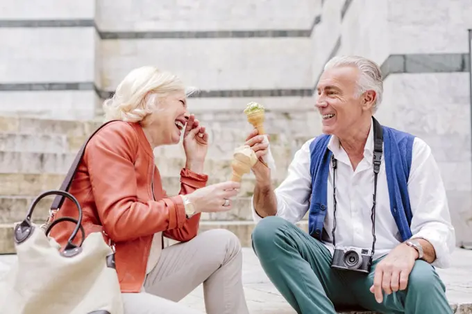 Tourist couple eating ice cream cones and laughing in Siena, Tuscany, Italy