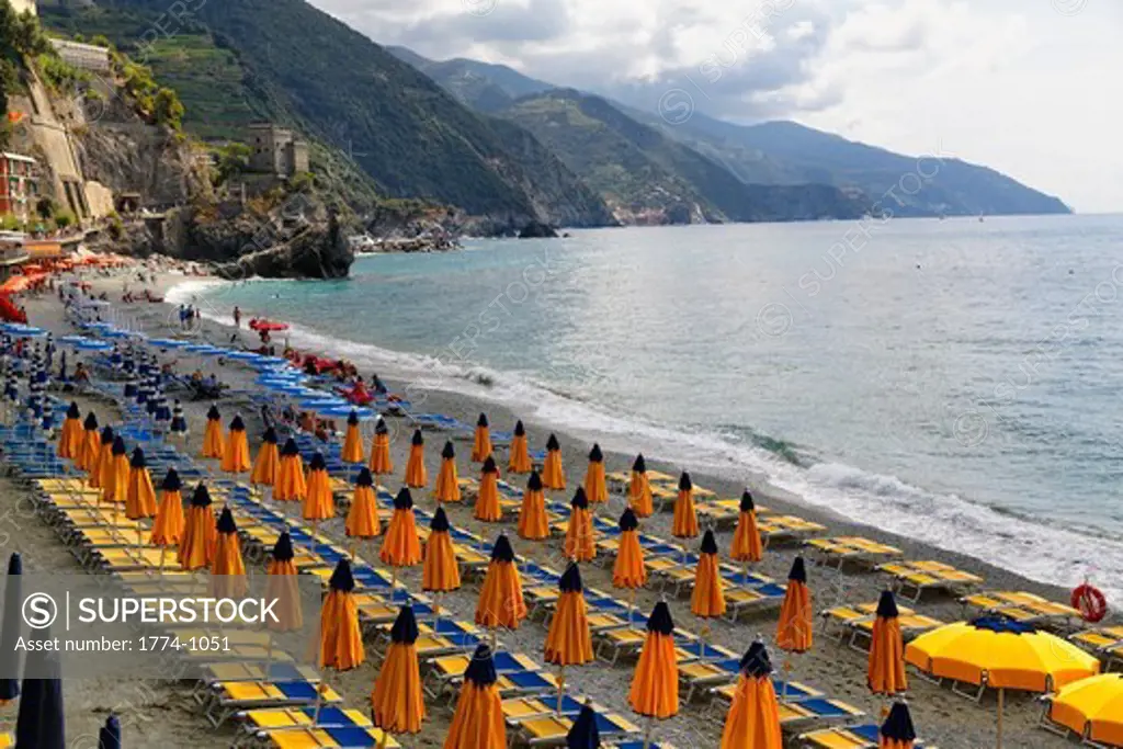 Italy, Liguria, Monterosso, Morning view of beach with lounge chairs and umbrellas