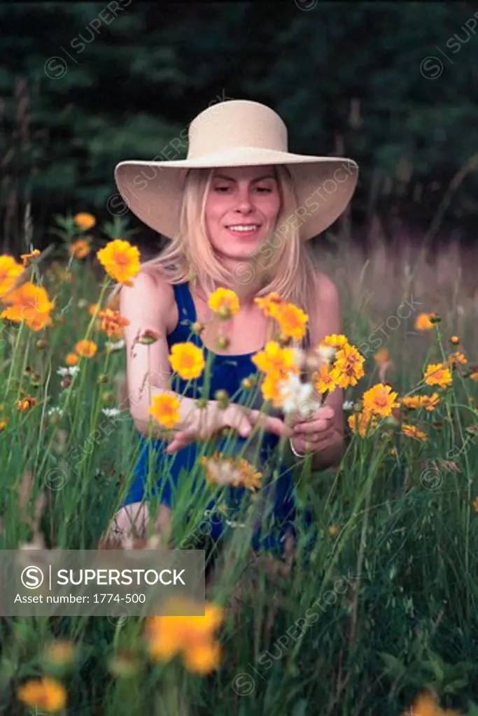 Young model plucking wildflowers in a meadow, New Jersey, USA
