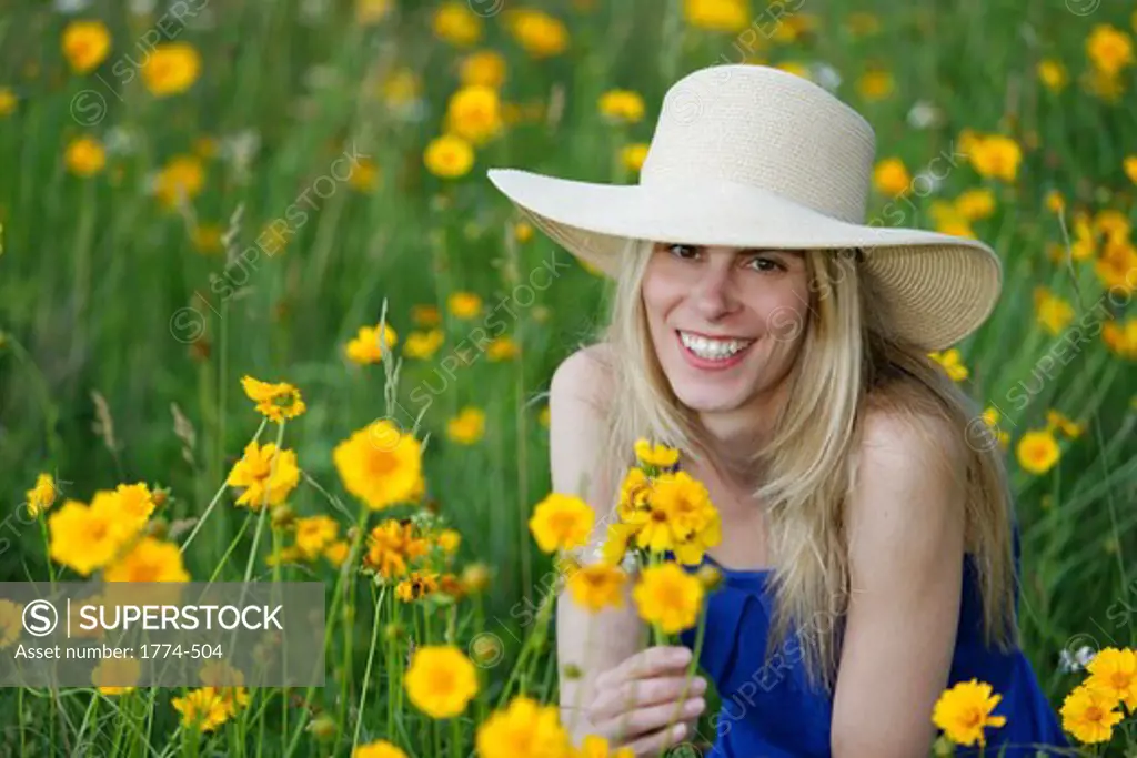 Young model holding wildflowers and smiling in a meadow, New Jersey, USA