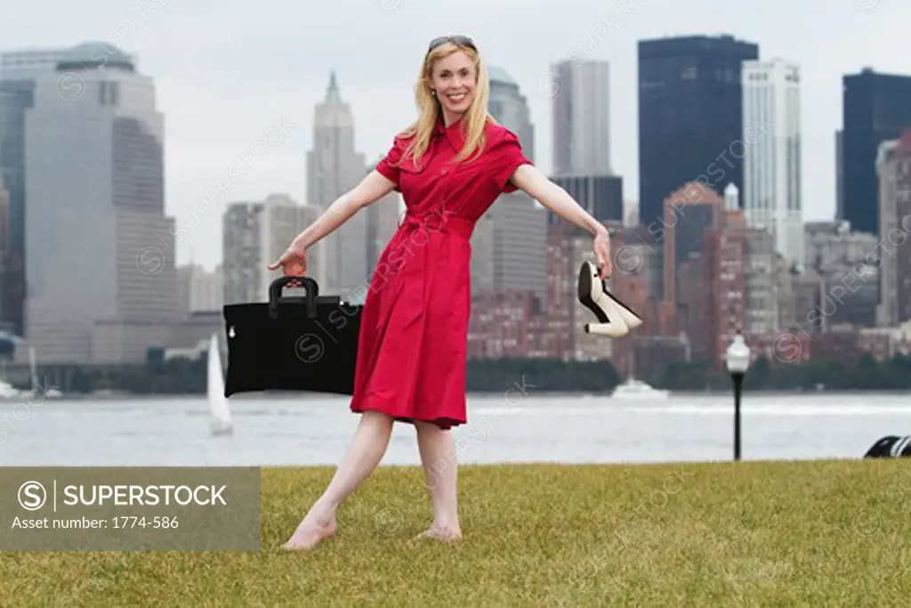 USA, New York City, Woman relaxing in park after work with Manhattan skyline in background