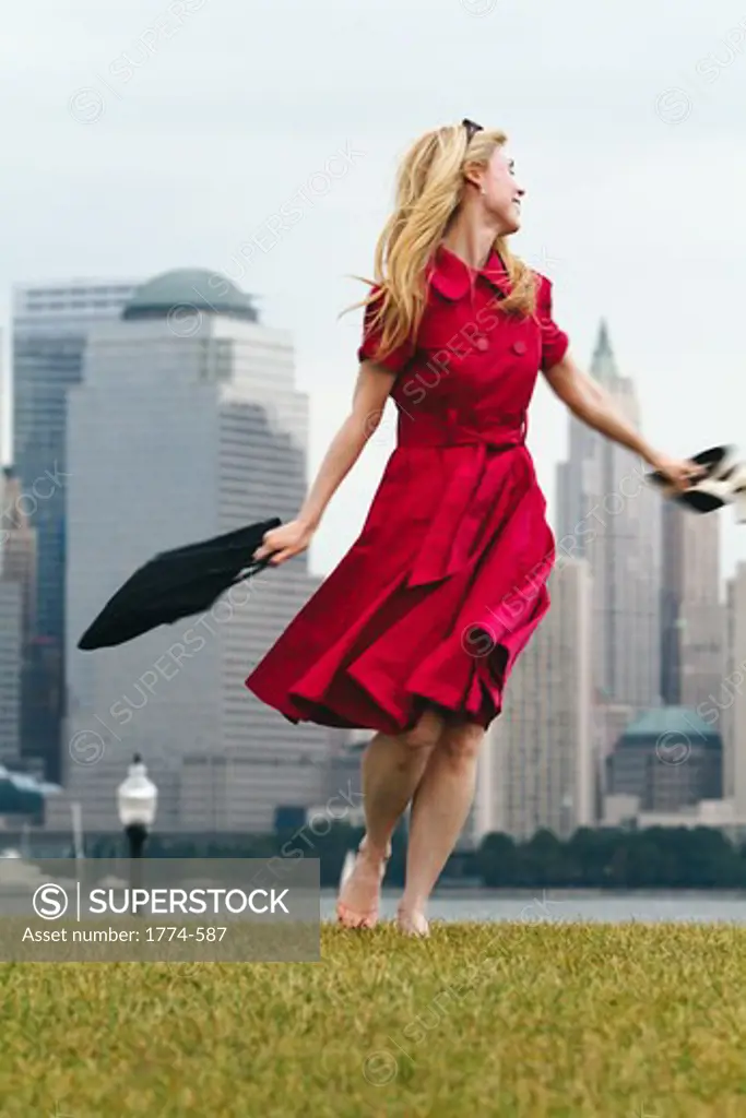 USA, New York City, Woman in red dress enjoying her free afternoon with Manhattan skyline in background