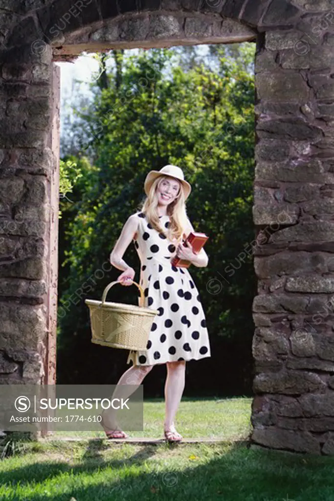 USA, New Jersey, Woman carrying picnic basket and book looking through old barn door and smiling