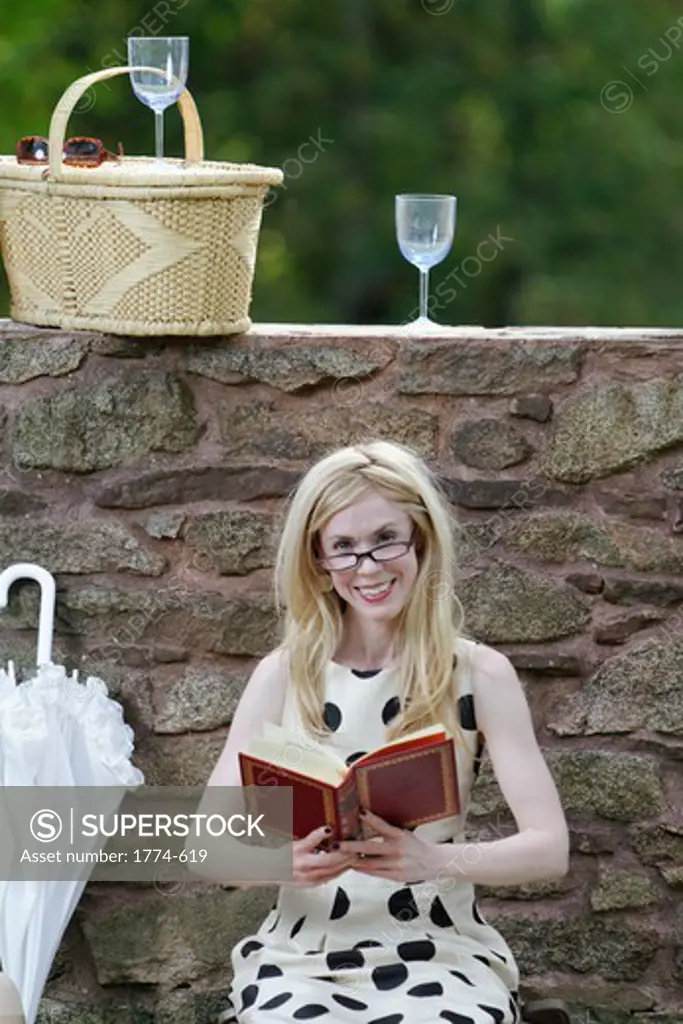 USA, New Jersey, Jersey City, Woman reading book during picnic and looking at camera