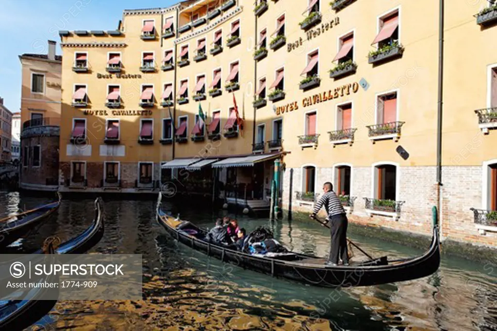 Tourists traveling in a gondola in a canal, Venice, Veneto, Italy