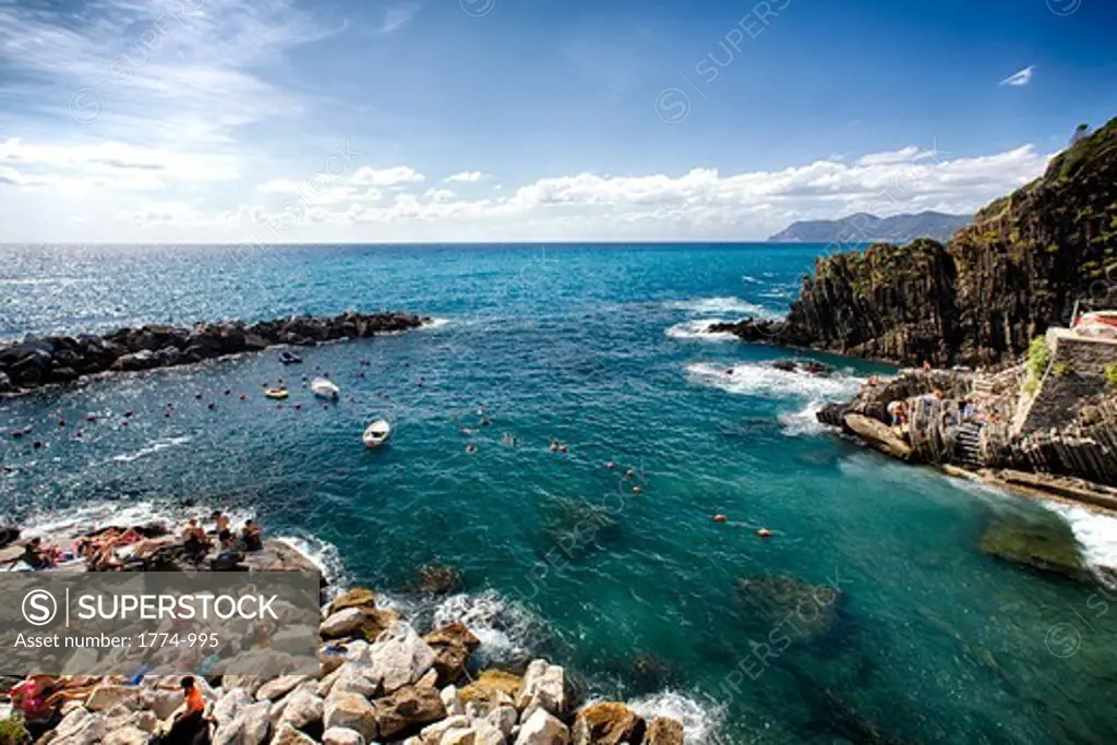 Italy, La Spezia Province, Liguria, Cinque Terre, Riomaggiore, High angle view of Rocky Bay with people swimming and sunbathing