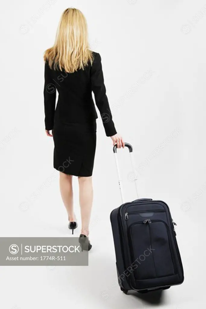 Rear view of a businesswoman walking with carry-on luggage