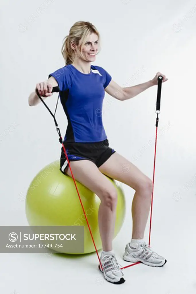 Woman Sitting on Exercise Ball and Pulling Up Exercise Rope