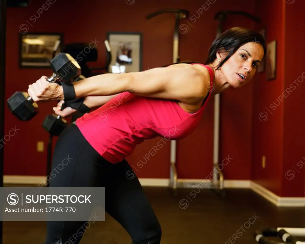 USA, New Jersey, Fit Mid Adult Woman Performing Arm Exercise with Weights Indoors