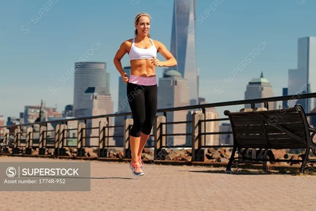 USA, New Jersey, Jersey City, Woman running in park with Manhattan skyline background