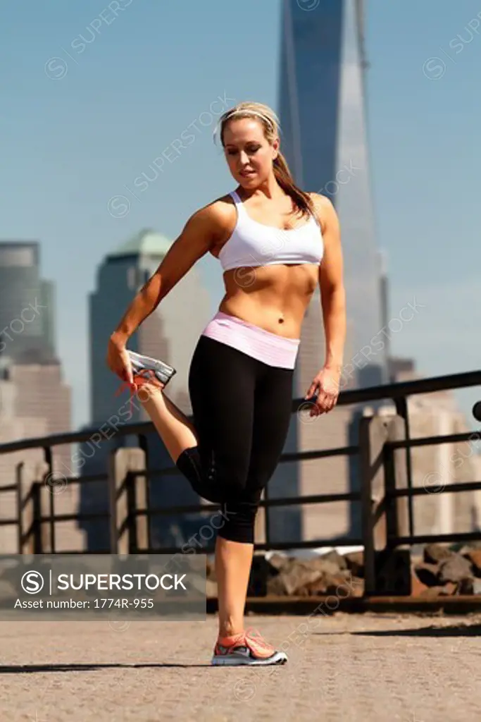 USA, New Jersey, Jersey City, Woman in sportswear stretching outdoors