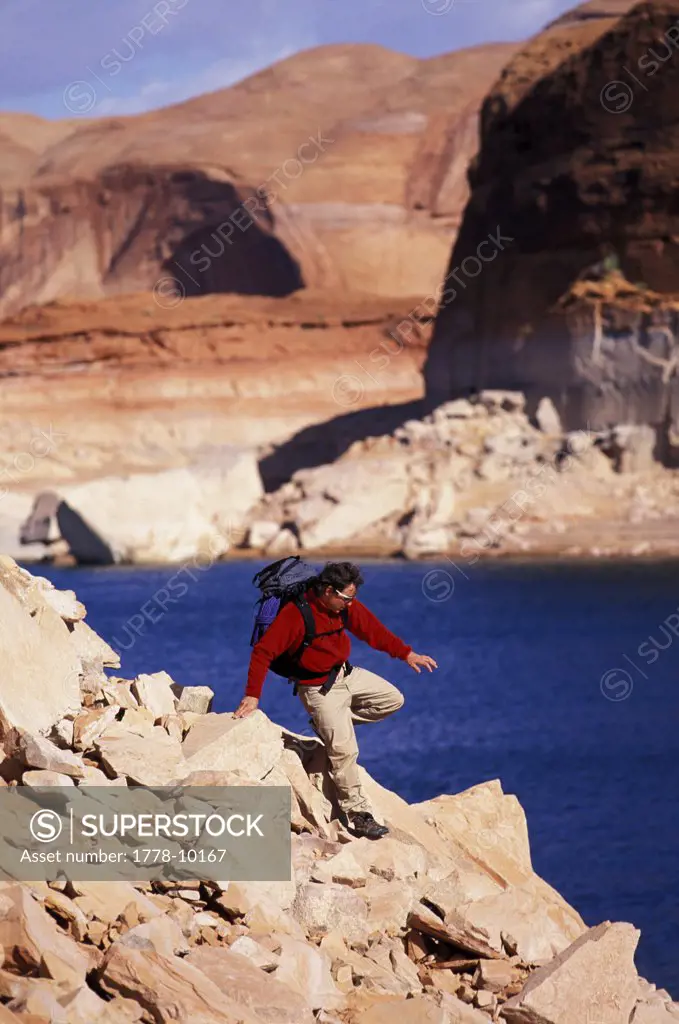 A man navigates a rocky slope on the edge of a lake