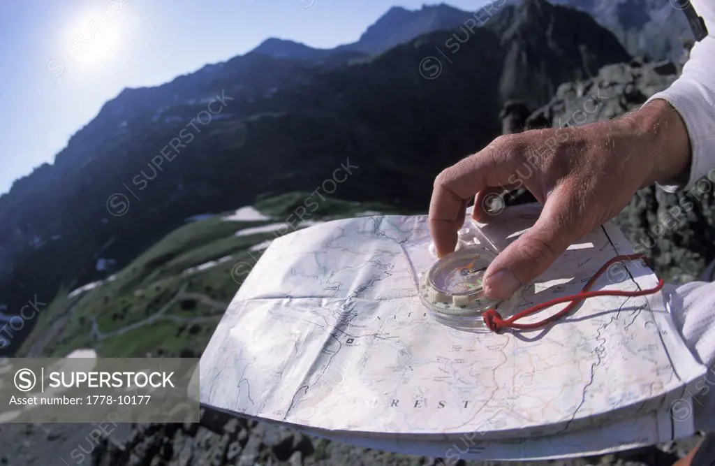 A man uses a compass and a topographic map to navigate through the mountains