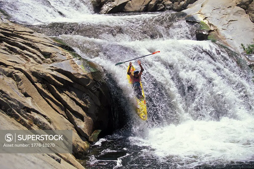 A man goes over a waterfall in a kayak