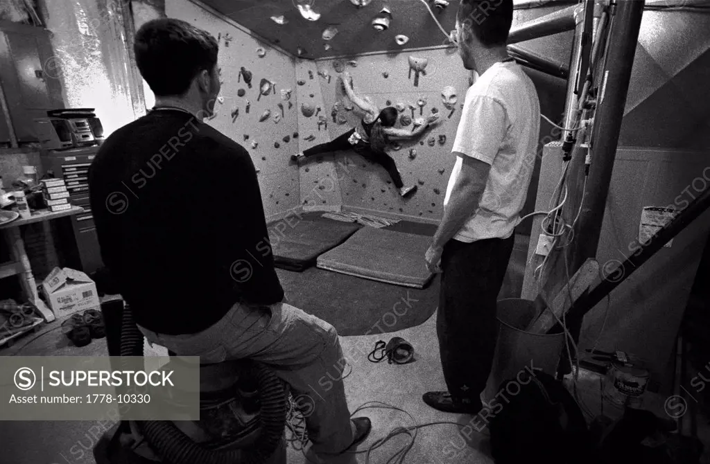 A group of friends hang out in thier garage that has been converted into an indoor climbing gym