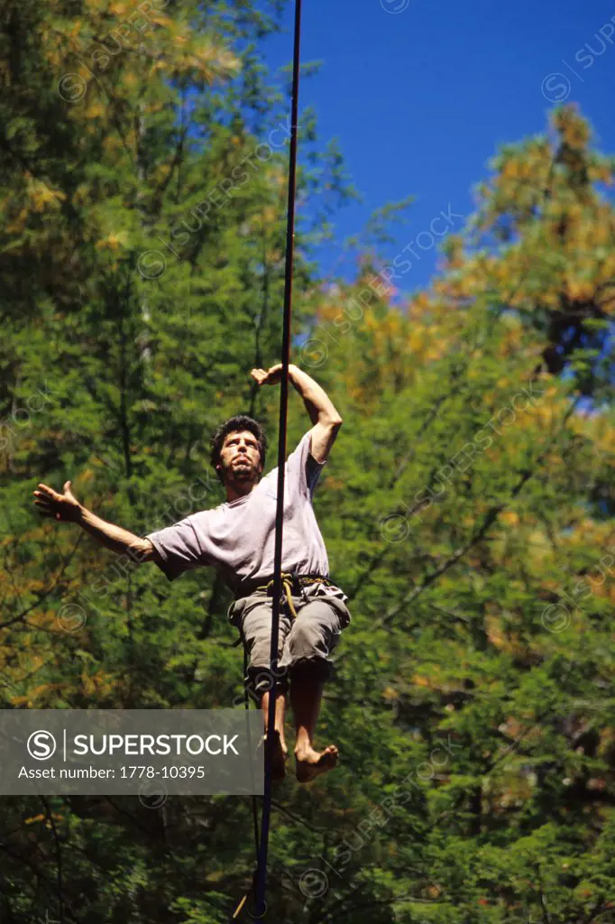 Slackline walker isolated against fall colors high above the ground in Slade, KY