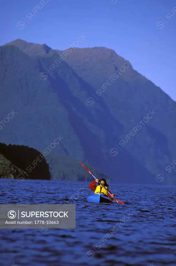 A woman paddeling in a kayak in the ocean