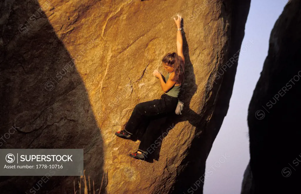 A woman climbing on a dificult bouldering route