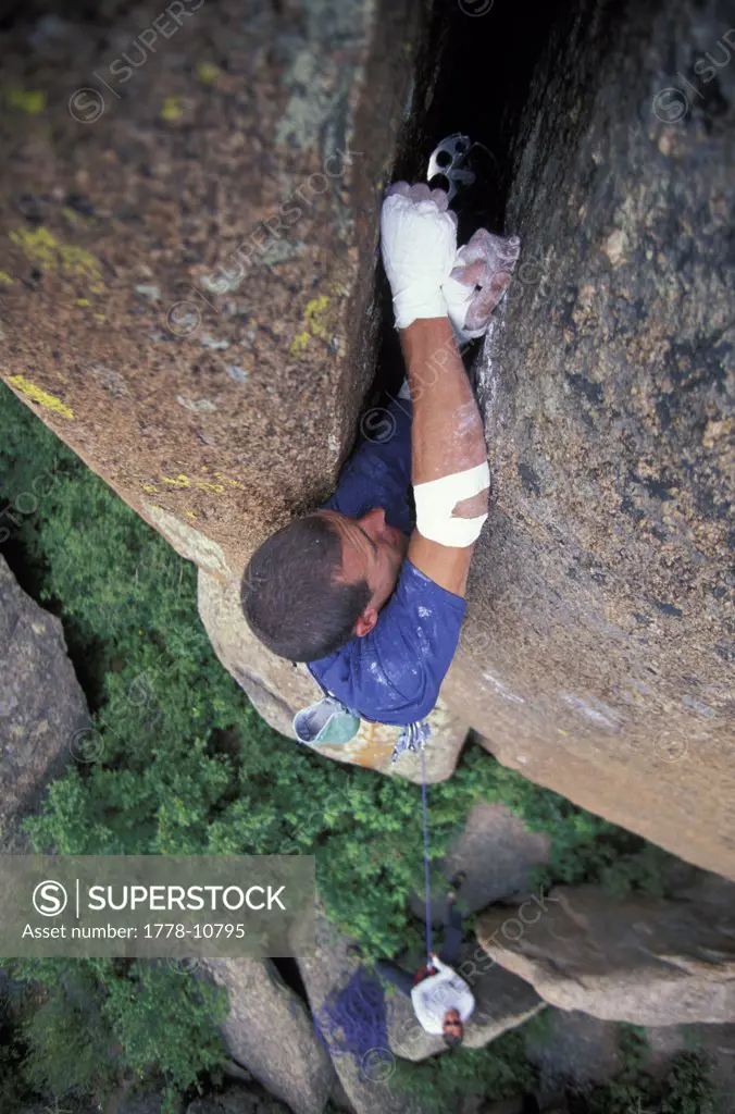 A rock climber places a cam in a crack while climbing a difficult route