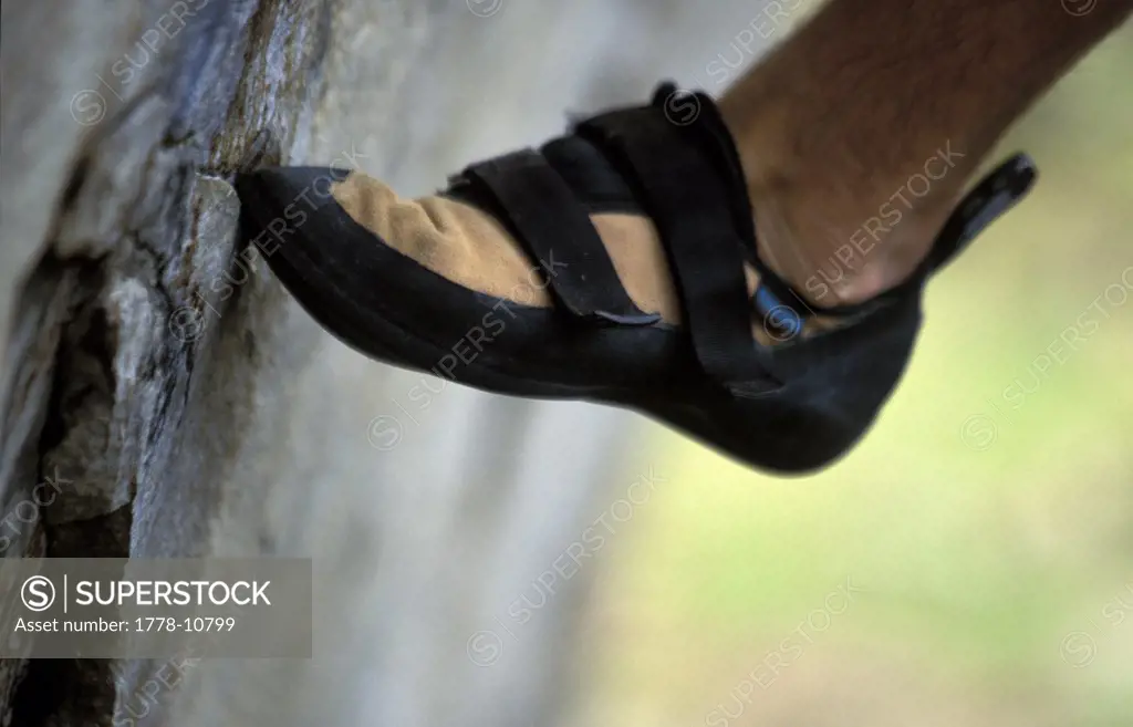 A climber's shoe pressed against a boulder
