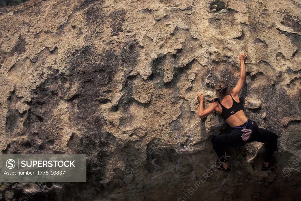 A female rock climber boulders on a bouldering route in a remote climbing area