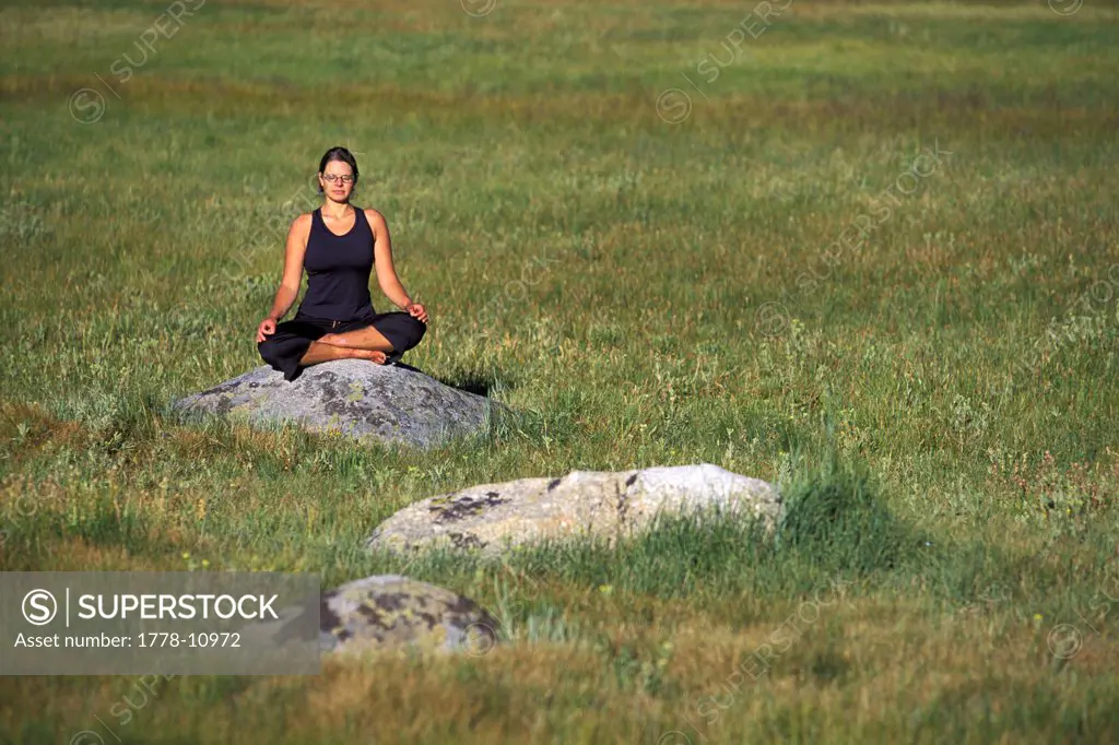 A woman meditating in a meadow