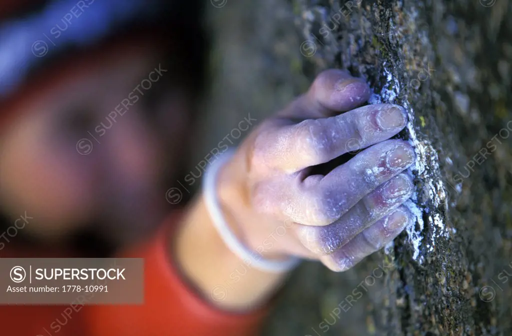 A female rock climber crimping a hold with her chalky hand