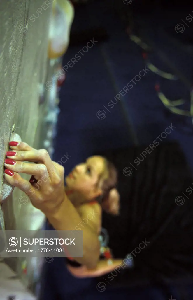 A teenage female rock climber climbing on an artificial climbing wall