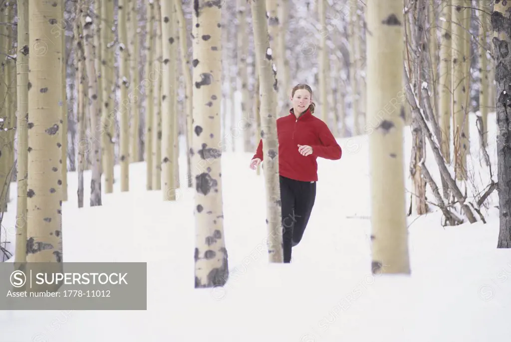 Woman running on snow covered trail