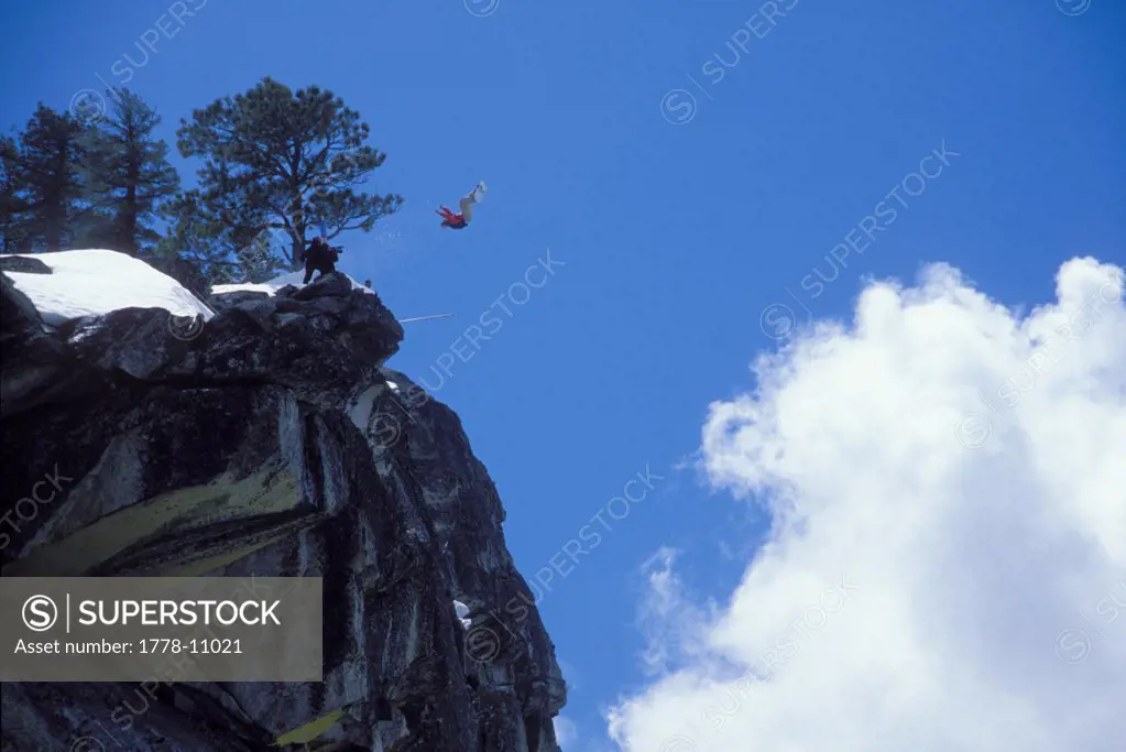 Snowboard-BASE jumper doing a backflip off a cliff near Lake Tahoe