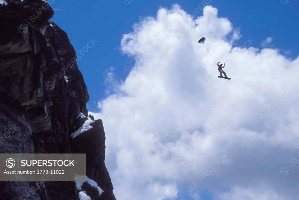 Snowboard-BASE jumper doing a backflip off a cliff near Lake Tahoe