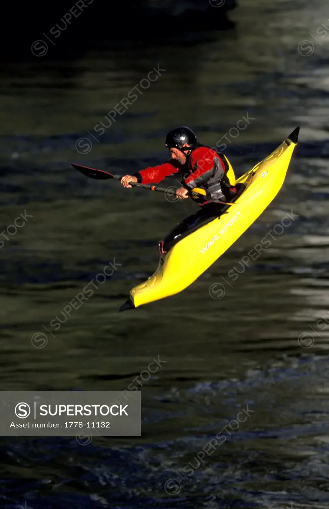 A man making a wet entry in his kayak into a river