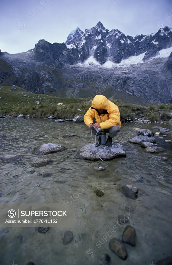 A man filters water from a mountain stream