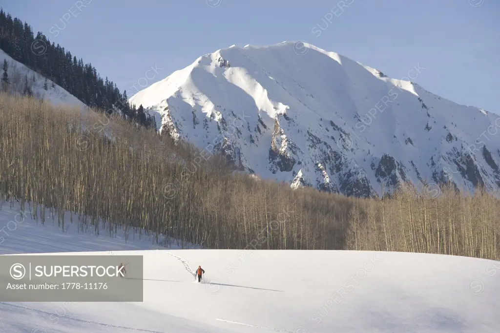 A couple snowshoeing with mountains in the background, Colorado