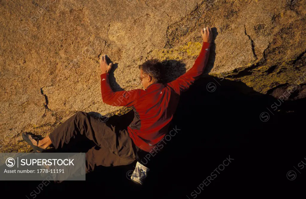 A male rock climber bouldering in the evening on an overhanging climbing route