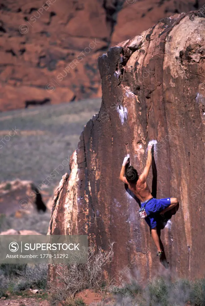 A male rock climber climbing in the desert on an overhanging bouldering route