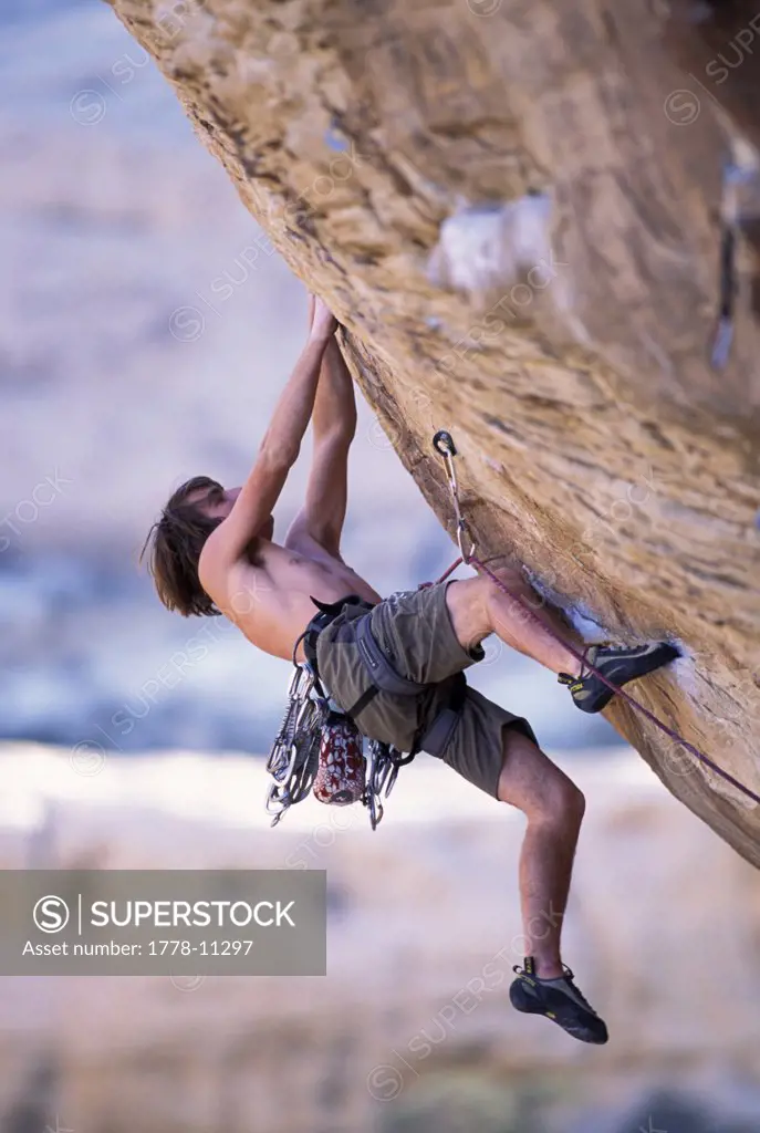 A male rock climber climbing in the desert on an overhanging route