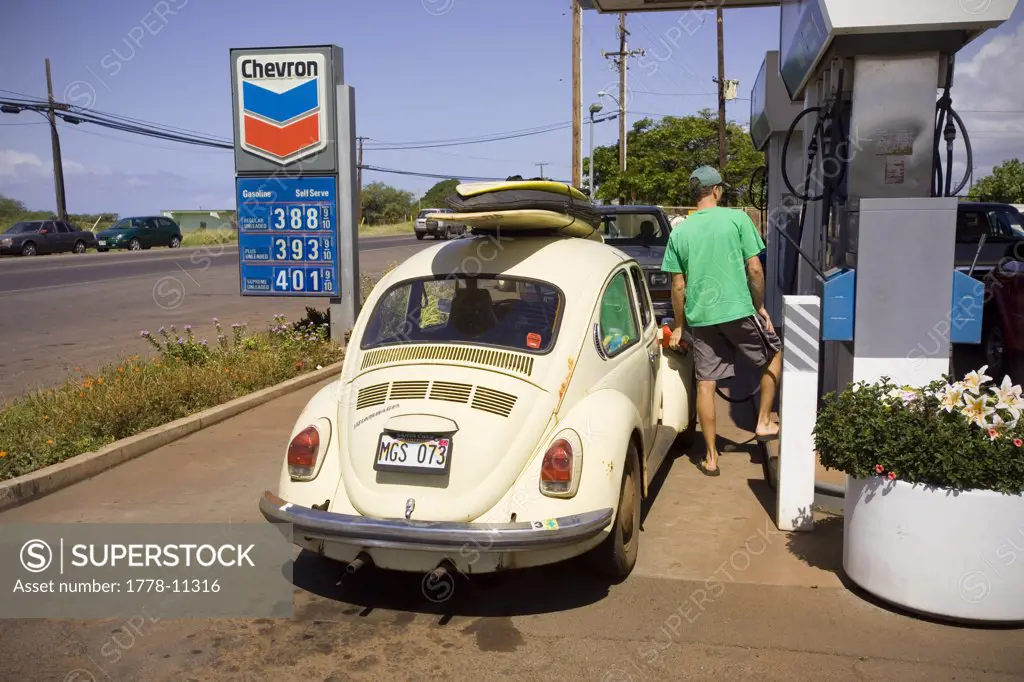 A surfer fills his gas tank with expensive fuel in Kaunakakai, Molokai, Hawaii