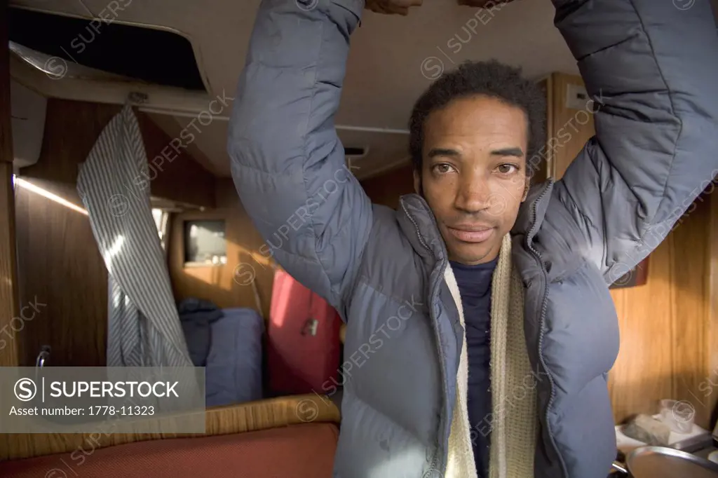 Portrait of black male with hands above his head in a trailer