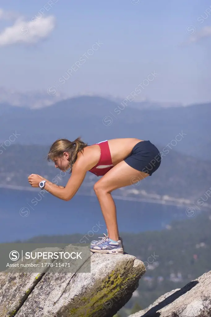 A Female Skier in Summer Practicing Her Racing Tuck on a Rock